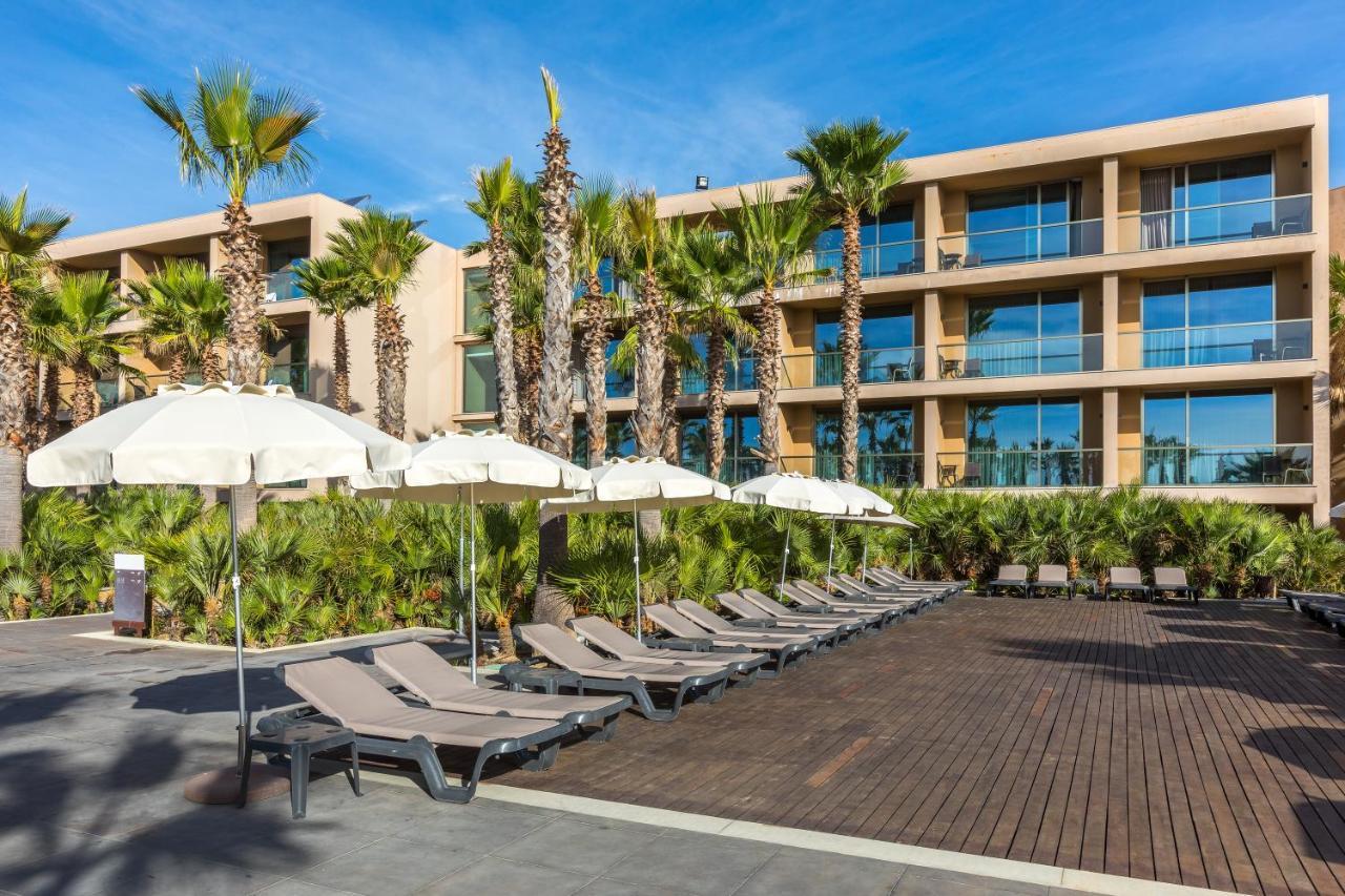 Ap Lago Montargil - Conference & Spa Exterior photo The photo shows a modern resort or hotel area featuring several lounge chairs lined up on a wooden deck. Each lounge chair is paired with a white umbrella, providing shade. In the background, there are palm trees, which add to the tropical atmosphere