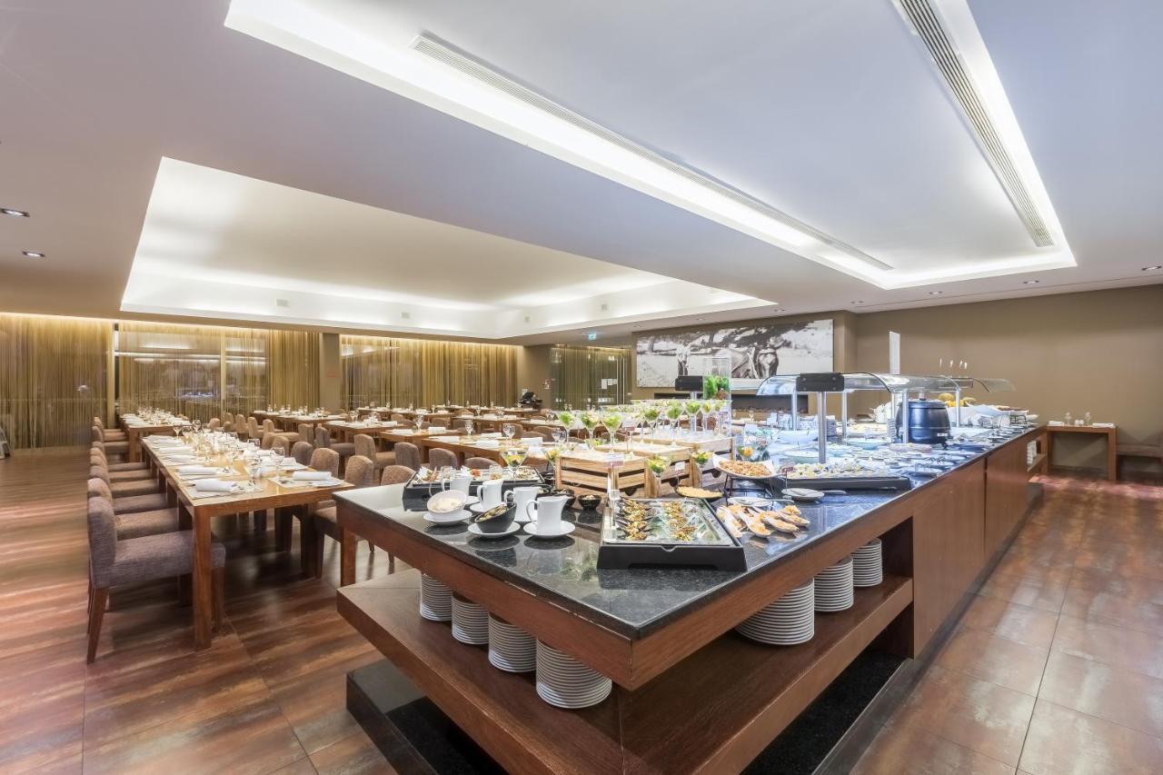 Ap Lago Montargil - Conference & Spa Exterior photo The photo displays a spacious restaurant interior, featuring a well-organized dining area with multiple tables set for patrons. In the center, there is a large buffet station filled with an array of food items. The decor is modern and elegant, with w