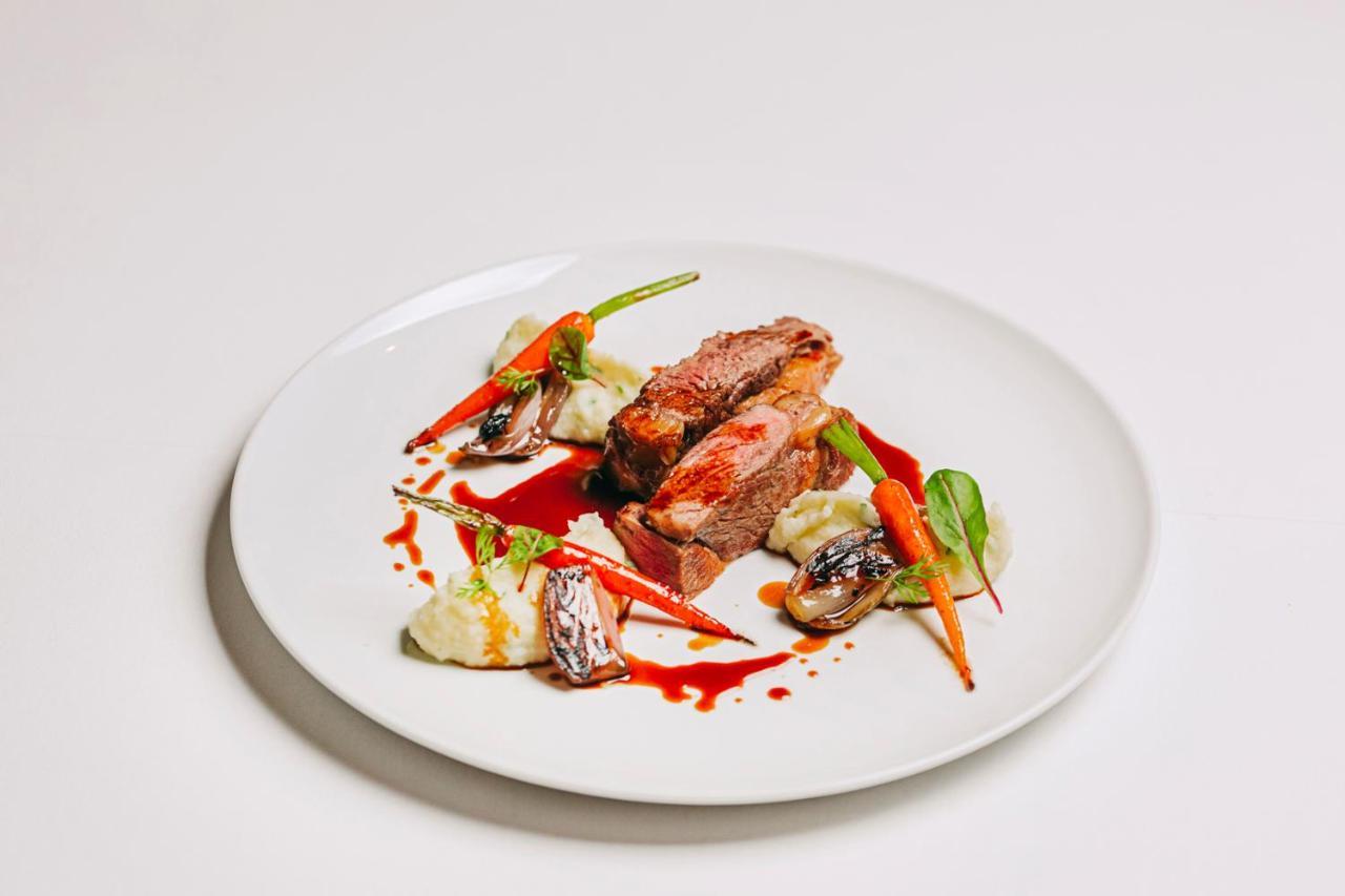 Ap Lago Montargil - Conference & Spa Exterior photo The photo features a beautifully plated dish. At the center, there are slices of a tender meat, likely beef, showcasing a juicy pink interior. Accompanying the meat are several elements: vibrant orange carrots, perhaps roasted or glazed, and dollops 
