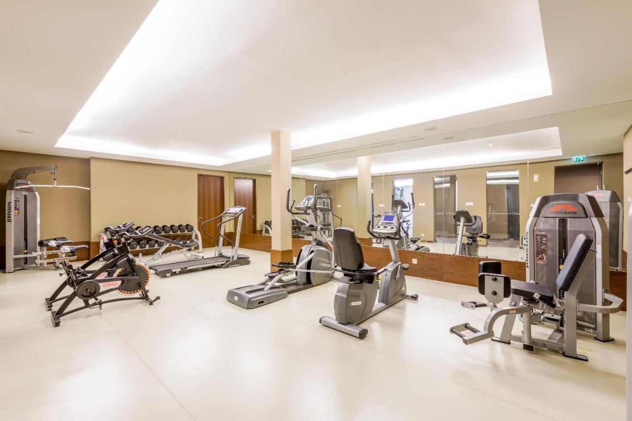 Ap Lago Montargil - Conference & Spa Exterior photo The image shows a modern gym interior featuring various exercise equipment. On the left, there are free weights and weight benches. In the center, there are multiple machines, including a stationary bike and an elliptical. The space is well-lit with 