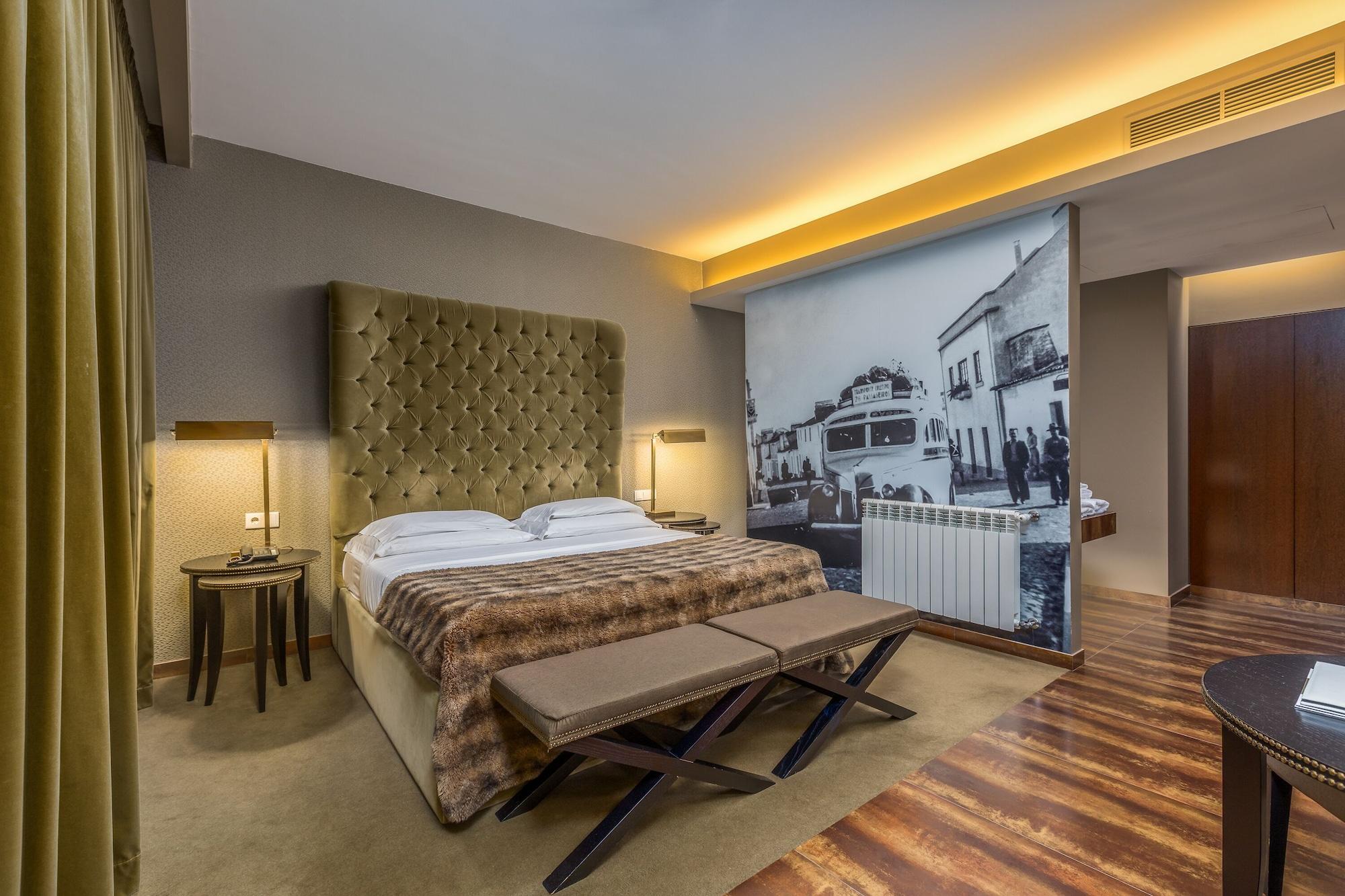Ap Lago Montargil - Conference & Spa Exterior photo The photo shows a modern hotel room featuring a king-sized bed with a tufted headboard, dressed in white linens and a decorative throw blanket. On either side of the bed, there are bedside tables with lamps. The room is well-lit, with an ambient ceil