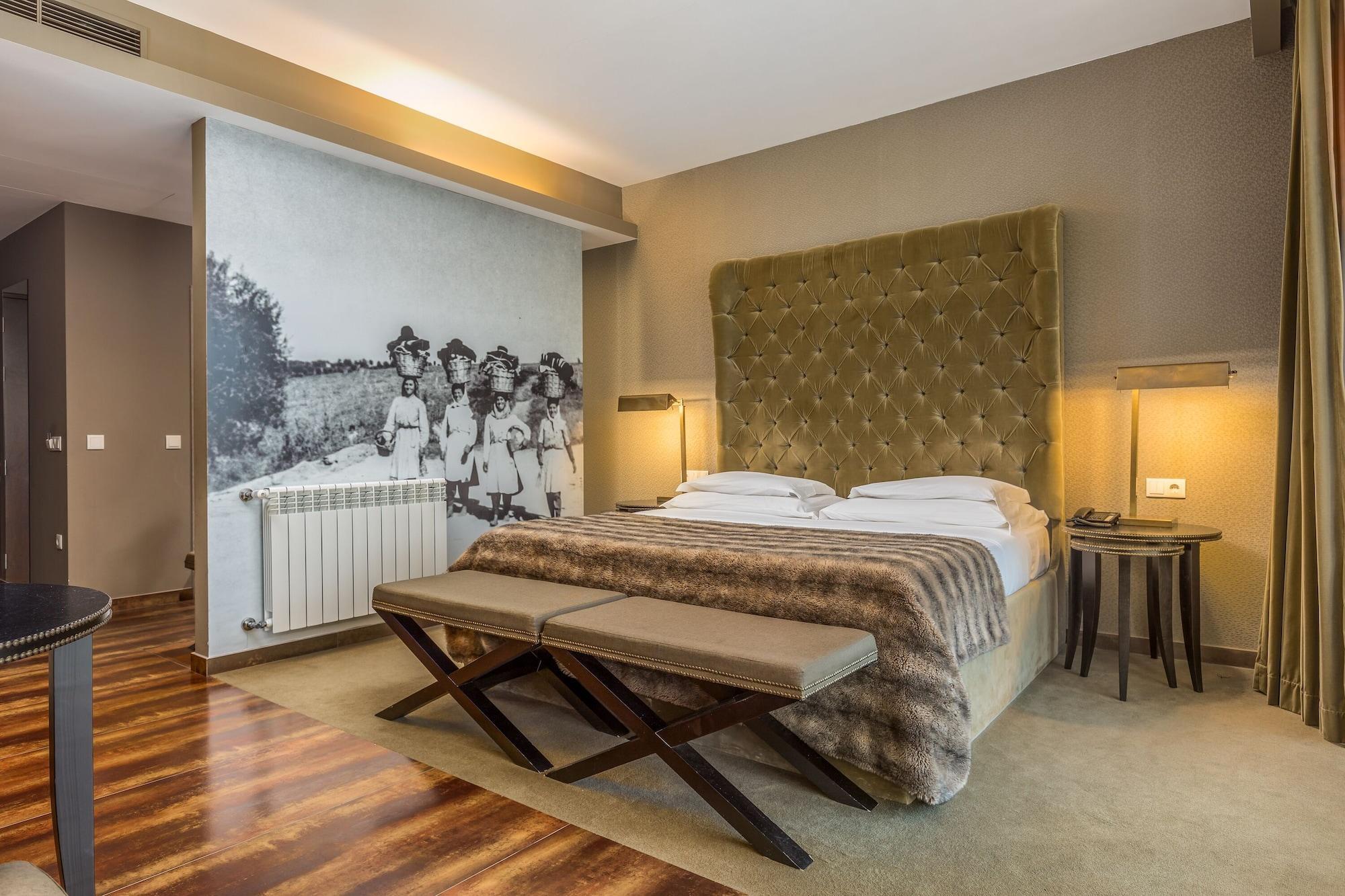 Ap Lago Montargil - Conference & Spa Exterior photo The photo shows a modern hotel room with a large, plush bed that has a tufted, green headboard. The bedding is white with a textured blanket at the foot of the bed. A decorative wall behind the bed features a black and white mural of children in a fi