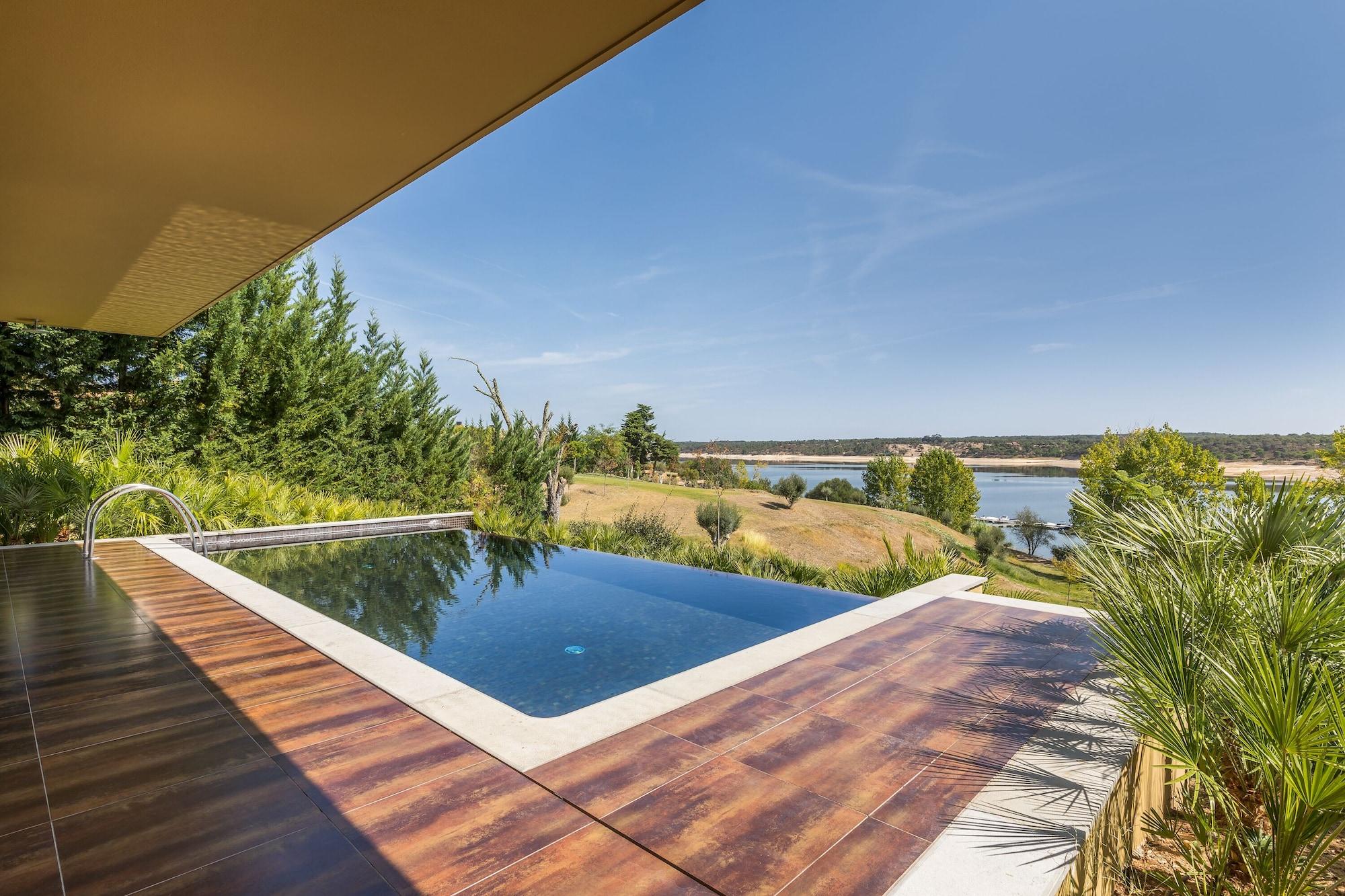 Ap Lago Montargil - Conference & Spa Exterior photo The photo shows a luxurious infinity pool situated on a terrace or deck. The pool features a sleek, modern design with a dark blue surface that reflects the surrounding scenery. In the background, there is a landscape of rolling hills and a body of w
