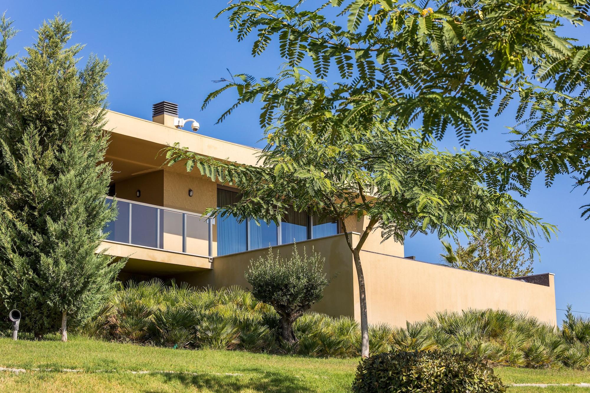 Ap Lago Montargil - Conference & Spa Exterior photo The photo showcases a modern house situated on a grassy slope. The house features a light-colored exterior with large windows and a balcony. Surrounding the building are several trees and landscaping that enhances the natural environment. The sky is 