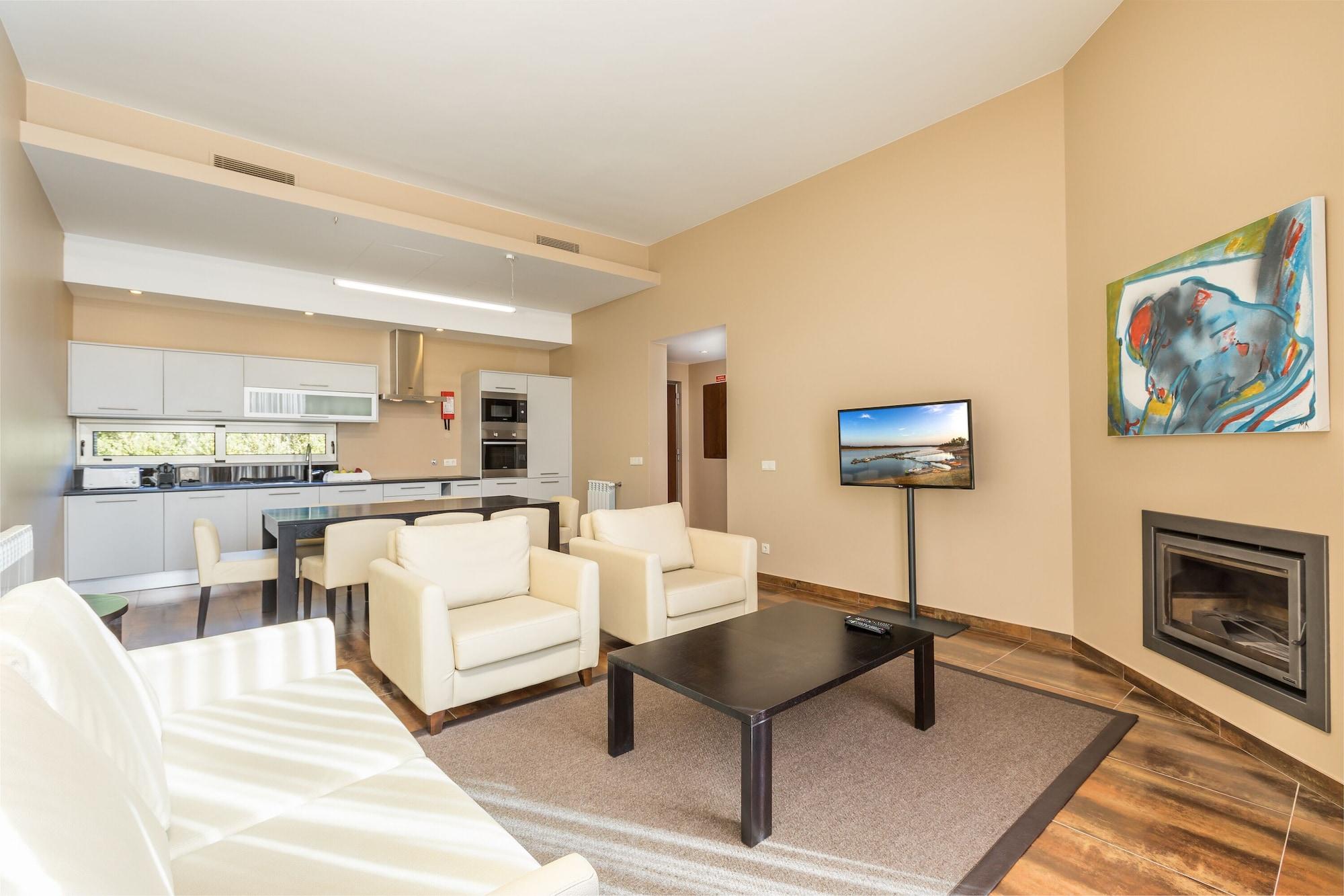 Ap Lago Montargil - Conference & Spa Exterior photo The photo shows a modern, spacious living area with a contemporary design. The room features light-colored walls and wooden flooring. 

In the center, there is a black coffee table surrounded by four white armchairs. A flat-screen TV is mounted on th